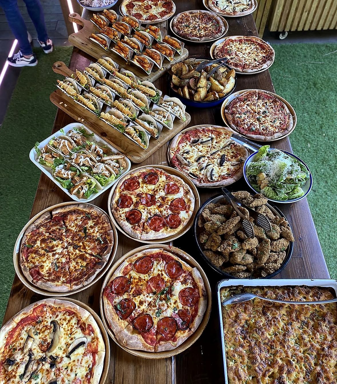 Party food table with stone-baked pizzas, tacos, chicken and mac and cheese